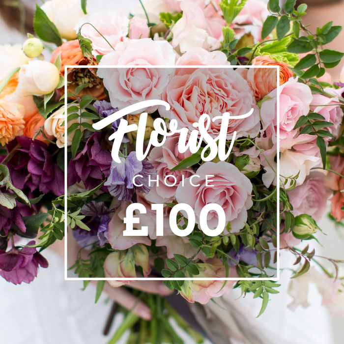A lush, hand-tied bouquet fills the frame with a harmonious mix of soft and dramatic tones, photographed in gentle daylight that highlights petal edges and the natural sheen of each bloom. Several full, ruffled pink garden roses are the immediate focal point, their layers of petals offering a tactile, almost fragrant impression. Complementary coral and peach ranunculus-like flowers add warmth and layered complexity, while thin-stemmed striped sweet peas in pale purple and white breathe lightness and movement through the arrangement. Deeper, plum-hued hellebore-like clusters create pockets of intense colour and textural contrast, helping the arrangement read as both romantic and sophisticated. Sprays of varied green foliage - from slender tendrils to broader matte leaves - are artfully interspersed to give a freshly gathered, garden-style silhouette. Centrally superimposed across the blooms is a thin white square containing the script 'Florist Choice', 'CHOICE' in smaller block letters beneath, and a bold '?100' at the base, clearly indicating this florist-selected option and price point. The bouquet is loosely gathered and held at the stems by hands in a pale sleeve, set against a softly blurred background so the eye rests on floral detail. Crafted with local sensibility and an eye for seasonal quality, this arrangement reflects the care you might expect from an independent shop near Stanmore High Street and the Jubilee line station; Flowers Stanmore would describe it as a refined choice for weddings, milestone birthdays or as a thoughtful luxury delivery to close friends and family.