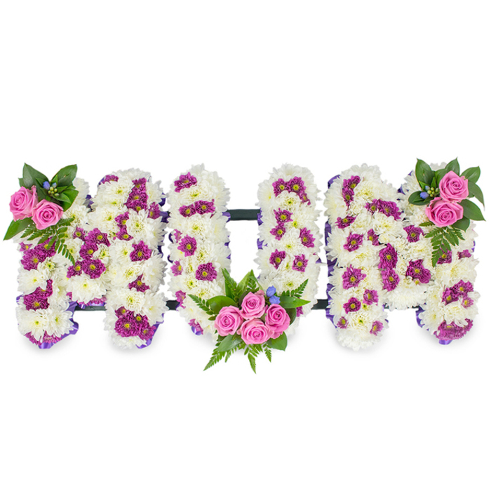 A poignant and carefully assembled floral tribute forming the word MUM, shown on a plain white background so every detail is visible. The letters are three-dimensional, each constructed from a compact, velvety mass of white chrysanthemums that give a soft, tactile quality and a tone of purity and calm. Interlaced among the white are pockets of rich magenta or deep purple spray flowers that add texture and subtle movement across the letter faces. Three clusters of pink spray roses provide the emotional focal points: a small accent at the top left of the first M, a more substantial bouquet cradled into the lower curve of the U, and a corresponding cluster at the top right of the final M. Lush dark green foliage-including feathery fern fronds-and a scattering of tiny blue accent blooms complete the palette with cool and grounding notes.

A delicate purple ribbon outlines the letters and a low-profile dark horizontal bar behind them keeps the trio united and stable when placed on a memorial easel or funeral stand. The craftsmanship is deliberate: stems are wired and trimmed so the surfaces stay seamless, the colours are balanced to read well under soft chapel lighting, and the scent is gentle rather than overpowering. This style of tribute is commonly chosen by families in the Stanmore area-from Stanmore Hill to the roads near Stanmore station and beyond-who want a personalised and dignified expression of grief and gratitude. The arrangement communicates respect, memory, and tender affection for a beloved mother with quiet refinement.