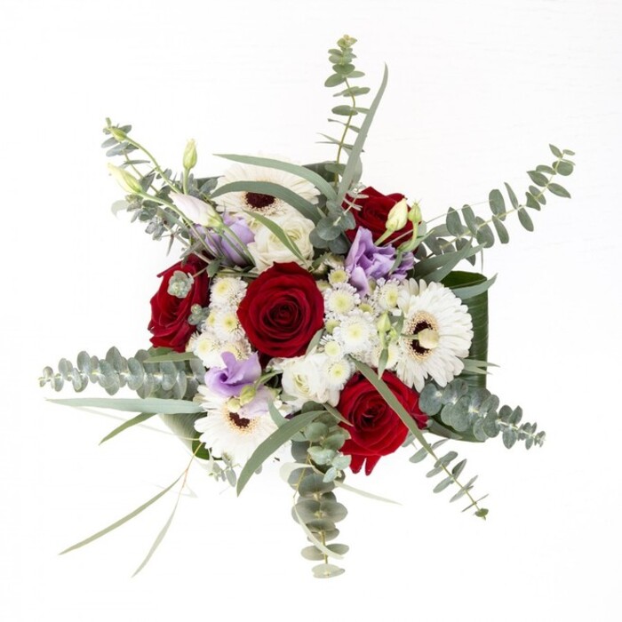 Crafted with the artistry and insight of a Stanmore florist, this bouquet strikes a poised balance between confident colour and timeless refinement. The rich, spiraled red roses anchor the arrangement, symbols of heartfelt affection and a familiar sight in the gardens off Stanmore Hill. Surrounding them, crisp white gerberas with espresso-brown eyes project calm and modernity, their petals like rays of light illuminating summer evenings in Canons Park. Interlaced are stems of light purple lisianthus-some gently budding, others softly blooming-bringing a contemporary softness and hint of nostalgia. Elevated by clusters of tiny white filler flowers, the bouquet possesses added fullness, reminiscent of mist rising over Bentley Priory. Sprays of silvery-green eucalyptus rise above, forming artful arcs and casting gentle shadows, their subtle fragrance lingering like the air after rain. At the vase's collar, lush broad leaves cradle the bouquet, providing an elegant frame and enhancing the fresh vibrancy through clear water and visible stems. Sent for occasions ranging from joyful celebration to tender remembrance, this arrangement embodies the care, tradition, and natural beauty found through every corner of Stanmore's close-knit community.