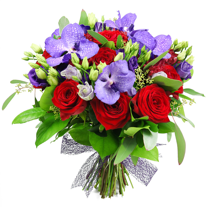 An opulent hand tied bouquet that speaks of romance and refined sophistication. Against a pristine white backdrop, deep red roses form a lush core, their velvety petals spiralling into rosettes of passion. Interwoven are purple Vanda orchids, broad petals veined with tiny speckles that give an exotic shimmer. Among them, eustoma lisianthus in lilac and indigo provide soft, cloud like pockets of light, some still in bud and others just opening, inviting a sense of anticipation. The arrangement is thick with greenery-large, glossy leaves and slender sprigs-that frame the blooms and lend depth. Fresh green buds punctuate the design, suggesting ongoing growth and vitality. The stems are gathered at the base and tied with a decorative dark mesh ribbon that creates a contemporary, painterly bow. The bouquet radiates romance and celebration, ideal for anniversaries, Valentine's Day, or a luxurious gift to mark a special moment. In Stanmore homes or at a wedding reception, it would command attention as a statement centerpiece. This piece can be delivered across Stanmore and the surrounding NW London area, bringing refined artistry to local clients.