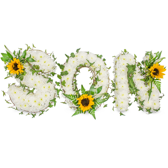A sculpted, three-dimensional floral tribute that clearly spells out SON in bold capital letters, each letter densely surfaced with hundreds of small, pure white chrysanthemums that create a plush, tactile texture like a cloud of petals. Interlaced through the white chrysanthemum base are trails of dark green ivy with characteristic lobed leaves and fine fern fronds that thread between blooms, introducing shadow, depth, and a living contrast that frames each letter. Strategically placed are three large sunflowers with luminous yellow rays and textured dark brown centres, acting as bright punctuation: one crowns the upper-left curve of the S, another fills the lower inner curve of the O surrounded by glossy foliage, and the third sits at the upper-right point of the N. The sunflowers draw the eye and impart a gentle warmth that balances the serene white chrysanthemums, conveying both grief and the memory of joy. The piece is photographed against a stark white background with soft directional lighting that emphasizes petal edges, leaf veins, and the assemblage's dimensionality, rendering colours vivid and true. A local Harrow and Stanmore aesthetic can be felt in the restrained, respectful composition, suitable for funeral chapels or a service near Stanmore tube station. This bespoke memorial piece reads as a loving, handcrafted statement of remembrance and is ideal for articles or pages describing personalized funeral tributes for a son.