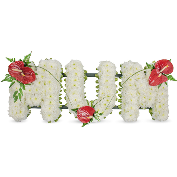 A poignant floral tribute spells MUM in elegant capital letters, each letter meticulously formed from hundreds of tightly packed white spray chrysanthemums that create a plush, voluminous surface. The chrysanthemums' pristine petals give the letters a soft, luminous quality under natural light, invoking feelings of peace and reverence. A subtle dark green skeletal frame holds the three-dimensional shapes together; it shows only as a thin outline at the edges where the blooms meet air, preserving the freestanding clarity of each letter. To introduce warmth and focus, three glossy red anthurium blooms-distinctive for their heart-like spathes and prominent yellow spadices-are artfully positioned: one gracing the upper left of the first M, another nestled into the lower curve of the U, and a third adorning the upper right of the final M. Each red bloom is gathered with sprays of rich green foliage, including soft fern fronds and broader leaves that add weight and texture, while long, arching blades of grass gently link the anthuriums and guide the eye across the composition. The overall effect is classic and restrained, ideal for a funeral, wake, or graveside service where relatives from Stanmore High Street, Canons Park, and beyond come to pay respects. The arrangement reads as both a public statement of love and an intimate, hands-on act of remembrance-carefully crafted to convey honour, tenderness, and enduring affection.