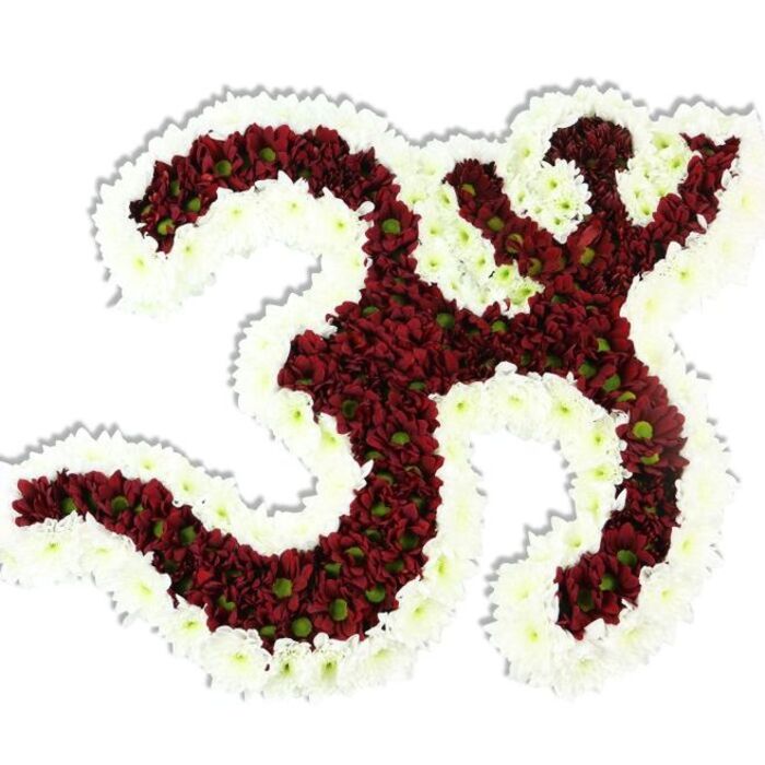 A striking floral Om (Aum) symbol occupies a studio-white stage, its iconic Sanskrit curves painstakingly formed from innumerable small, chrysanthemum-like blooms. The interior mass is composed of rich, dark red to maroon pompon flowers, each cluster compact and textured, many revealing a small lime-green centre that adds a living, botanical highlight to the somber tone. Surrounding and sculpting the emblem is a robust, flowing border of pristine white chrysanthemums whose petals are fine and ruffled, producing a crisp contrast that defines the symbol's loops, the crescent-and-dot motif, and the extended sweeping stroke. The arrangement's construction feels both architectural and tender; the petals are densely packed to create a soft yet defined relief, and the whole piece casts a modest drop shadow on the white plane beneath it, accentuating its three-dimensional volume. There's a subdued, late-summer green-earth scent suggested by the flowers, a comforting, natural perfume that suits moments of reflection or devotion. As a floral tribute this work is dignified and contemplative - ideal for memorial services, temple displays, or quiet gatherings for mantra and meditation. As a Stanmore-based florist I picture this piece framed near the gentle walkways of Stanmore Common or brought to a ceremony at Bentley Priory, where its colours and calm presence would feel at home among local rituals and remembrances.