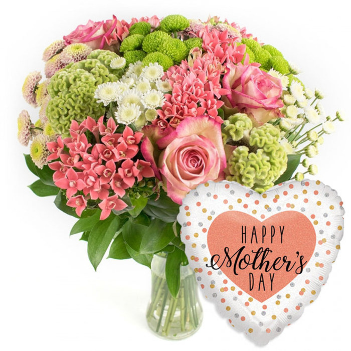 The photograph showcases a luxurious Mother's Day floral gift arranged as if by a skilled local florist serving Stanmore. Against a clean, white background, a clear glass vase stands slightly left of centre, filled with straight green stems that support a full, rounded bouquet. The colour story is a harmonious blend of pink, coral, crisp white, and fresh lime green. Large, open pink roses with gently darker edges immediately draw the eye, their velvety petals suggesting softness and love. Tucked around them are numerous tight clusters of coral-pink flowers, reminiscent of kalanchoe, each group resembling a tiny bouquet in itself and providing a richly textured contrast. Lime-green button chrysanthemums dot the design with neat, round shapes, while velvety, frilled chartreuse blooms add a unique, sculptural element, like small mossy cushions nestled among the petals. Scattered through the arrangement are airy white spray chrysanthemums and other small, daisy-like blossoms that brighten the bouquet and lend a light, celebratory feel. Deep green foliage surrounds and supports the flowers, filling in any gaps and ensuring a beautifully domed shape, like a centrepiece ready to grace a Stanmore dining table for a family gathering. To the lower right of the vase floats a shiny heart-shaped foil balloon, tilted at a slight angle. Its white or pale silver background is sprinkled with irregular polka dots in shimmering gold, silver, and peach tones, creating the impression of gentle confetti. At the heart of the balloon, a solid peach-coloured heart displays the greeting HAPPY Mother's DAY in black lettering, part bold caps and part elegant script. Together, the bouquet and balloon embody a thoughtful, joyful tribute to mothers, evoking warmth, gratitude, and celebration.