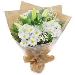 An elegant bouquet that celebrates the purity of white with the calm, attentive touch of a local Stanmore florist. The composition centers on generous clusters of pristine white chrysanthemums-each daisy-like head ringed by fine, overlapping petals and a warm, yellow eye-creating a cheerful, familiar base. From this bed of white, several pale green-yellow lily buds extend upward, some subtly striped and tightly furled, promising soft, fragrant blooms in the days ahead and adding a poised vertical rhythm to the arrangement. Interlaced throughout are delicate clouds of baby's breath (Gypsophila), their tiny white florets lending an ethereal, filigree texture that softens the bouquet's silhouette. Deep green foliage provides a rich, cooling backdrop that makes the whites read as luminous and pure. The flowers are hand-tied and wrapped in an inner layer of rustic brown kraft paper with a glossy cellophane outer wrap that protects the stems while allowing the arrangement to read cleanly against its surroundings; the gathered base is secured with a neat bow, ready for hand delivery. The scent is fresh and understated, a green, dewy whisper rather than overpowering perfume. This bouquet is both versatile and dignified-a thoughtful token for birthdays, new home welcomes, quiet congratulations, or moments of remembrance. Flowers Stanmore prepares arrangements like this for same-day delivery across the local area, from Stanmore Common to Harrow, with the kind of care regular customers expect from a neighbourhood florist.