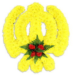 Framed against pure white, this floral rendition of the Khanda emblem reads like an emblem of faith sculpted in blooms. Thousands of small, bright yellow chrysanthemum heads are densely arranged to map every curve - the circular chakram, the central double-edged sword, and the two crossed kirpans - creating a soft, plush texture that holds its shape while appearing almost luminous. The yellow petals are compact and slightly ruffled, catching light to create subtle highlights across the symbol's sweep; a soft grey shadow beneath confirms its physical presence and gentle weight. Anchoring the design is a focused cluster of five to six rich red roses at the centre, their velvety faces tightly gathered and cushioned by deep green fern fronds that add a crisp, cool backdrop. This concentrated red centre reads as a point of warmth and respect amid the expansive yellow field, communicating solidarity, remembrance and love. The arrangement's craftsmanship is precise: the proportions of the Khanda are faithfully observed so the symbolism remains clear, and the choice of hardy chrysanthemums ensures longevity for ceremonial use. As a local Stanmore arrangement, I picture it set at a memorial or cultural event near Stanmore High Street or delivered softly to a family home after a service at a nearby gurdwara, its gentle floral scent lending calm to an otherwise heavy day.