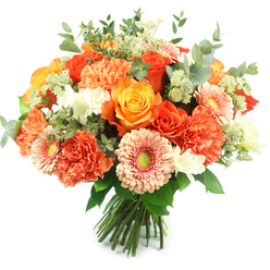 Bathed in clean daylight against a brilliant white backdrop, this hand-tied bouquet captures a sunlit moment in floral form. Dominating the centre are several fully opened roses in deep orange and sunny golden-yellow tones, their layered petals offering a luxurious, velvety texture. Coral and peach carnations fill the composition with ruffled volume, creating a soft, tactile cushion around the roses, while peachy gerbera daisies peek through with broad, delicate petals and slightly green centres that bring a playful lift. Tiny white filler blooms-suggestive of freesia or small spray flowers-nestle between the larger heads, providing bright punctuation and an airy lightness. Wisps of pale green, astrantia-like clusters add a feathery, romantic detail, and generous sprigs of silvery eucalyptus with rounded grey-green leaves thread through the design, contributing a cool, resinous fragrance and visual respite from the warm palette. The stems are bound neatly at the base in a classic hand-tied style, ready for presentation or a glass vase. As a florist who arranges daily for families around Stanmore Hill and the High Street, I picture this bouquet greeting guests at a birthday brunch or arriving as a thoughtful thank-you. Available for local delivery, Flowers Stanmore often pairs these same textures and tones for seasonal celebrations, bringing a feeling of warmth and handcrafted care to homes and events in the area.