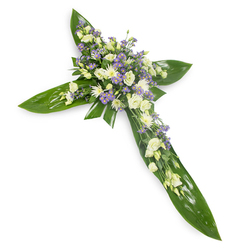 Viewed from a slightly elevated perspective on a stark white field, this floral cross combines botanical structure and soft florals to create a composed, consoling tribute. The frame of the cross is formed from large, lustrous green leaves-tropical in character with obvious veins and a waxy surface-that establish a strong, verdant geometry. At the intersection and extending along each arm are carefully arranged clusters of pale blooms: creamy ivory lisianthus with their gently unfurling layers and small, crisp white daisy-like chrysanthemums that add a lift of brightness and texture. Interspersed are delicate sprays of pale lavender or light purple tiny flowers, probably limonium or miniature asters, which introduce a cool whisper of colour and visual depth. Thin sprigs of finer green foliage peek through the blooms, softening edges and lending an understated, natural finish. The lighting is soft and diffuse, catching the leaves' gloss and revealing petal translucence, resulting in a quiet, contemplative mood reminiscent of early morning at Bentley Priory or a reflective walk through Canons Park. The overall effect is respectful and serene, appropriate for funeral services, chapel displays near Stanmore tube, or remembrance moments in a church hall; it speaks of steady faith and tender memory rather than flamboyance. The sensory suggestion is of cool green freshness with a faint floral sweetness-an arrangement that comforts and holds space for those grieving.
