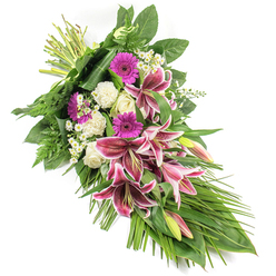This elegant sympathy spray, photographed on a crisp white background, appears as a sweeping diagonal composition of deep pink and white blooms surrounded by lush greenery. From the clustered stems at the top left, the flowers and foliage spill downward and outward to the bottom right, forming a graceful crescent or teardrop shape that naturally guides the eye. Dominating the centre are opulent Stargazer lilies, their large petals painted in intense fuchsia-pink, edged with bright white and flecked with dark burgundy speckles near the throat. Some lilies are fully open, showcasing their dramatic star-like form, while others remain in smooth green buds tinged with blush, symbolising love that continues beyond the moment. Among them, magenta gerbera daisies add vivid, round bursts of colour, while creamy white roses introduce classic elegance, their petals layered in tight spirals and partially open blooms. Soft, ruffled white carnations nestle between the larger flowers, contributing a pillowy texture and a sense of gentleness. Tiny white daisy-style blossoms are scattered throughout, giving an airy lightness and fine detail. The floral display is cradled in a rich mix of foliage: broad, glossy leaves create a strong, dark green backdrop; feathery fern fronds lend movement around the edges; and long, slender, blade-like leaves extend beyond the flowers, emphasising the spray's length and flowing character. Even studio lighting ensures every texture and colour reads clearly, as if you were viewing it in person at Flowers Stanmore before it is delivered to a local chapel, synagogue, or home near Stanmore Hill. Radiating quiet respect and affection, this spray is ideal for expressing condolences and offering comfort at times of farewell.