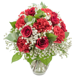A beautifully composed arrangement of red and white flowers is displayed in a clear glass vase, photographed against a clean white background that highlights its classic elegance. At the heart of the bouquet, deep crimson red roses stand tall, their velvety petals curled into precise spirals that speak of romance and enduring affection. Around them, generous clusters of ruffled red carnations create a plush halo of colour, each bloom made up of countless soft, feathery petals that add fullness and a sense of joyful abundance. Woven between these rich red tones, clouds of white baby's breath bring lightness and contrast, their tiny blossoms scattered along slender stems like delicate lace, giving the whole piece a gentle, dreamy softness. Fresh greenery, from glossy dark rose leaves to rounded eucalyptus in a soft, silvery shade of green, peeks out from among the flowers, adding natural structure and a calming, herbal freshness. The bouquet is arranged into a smooth, rounded dome, every stem thoughtfully placed so that the reds, whites, and greens feel perfectly in balance, showcasing the practiced hand of a local florist used to creating romantic gifts for homes and celebrations all around Stanmore. The simple glass vase, filled with clear water, reveals the carefully prepared stems and gives the composition a grounded, polished look without drawing attention away from the blooms. The overall mood is intimate yet celebratory, ideal for an anniversary dinner in a Stanmore living room, a Valentine's surprise after a stroll through Canons Park, or a special delivery to say "I love you" or "thank you" with the timeless combination of red roses, red carnations, and delicate white baby's breath.