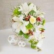 An artfully styled floral composition, perfect for a Stanmore wedding or anniversary dinner, is set against a calm, textured beige background that gently fades behind the blooms. At the centre of the image, a round white wicker basket sits on a pristine white table, its open weave giving a light, handcrafted feel. From this basket, a lush arrangement of white and green flowers fans out in a rounded shape, with just a touch of cascading movement to one side. Several large white lilies are the stars of the display, their trumpet-shaped blooms fully open and generously sized, each petal curving outward to reveal subtle speckling and pale stamens that suggest a delicate fragrance. Near the upper centre, a single cream-to-ivory rose is nestled among the lilies, its layered petals forming a soft spiral and drawing the eye like a quiet focal point. On the right side, a gentle waterfall of white phalaenopsis orchids drapes downward, each bloom with wide, velvety petals and a graceful, slightly nodding form that recalls the cascading bouquets favoured at Stanmore church weddings. Around these main flowers, rich foliage fills out the structure: fine, feathery greens, broader glossy leaves, and bright green pom-pom flowers that add playful texture and depth. Tiny white baby's breath blossoms are sprinkled throughout, creating a light, airy veil between the larger blooms, while small clusters of ruby-red berries add lively flashes of colour and a festive note, ideal for winter receptions near Stanmore Broadway. The arrangement rests securely on the white tabletop, with faint reflections softly anchoring it in space. To the left of the basket, two white decorative spheres made from interwoven strands mirror the basket's texture and introduce a contemporary sculptural accent. The result is a centerpiece that feels serene, luxurious, and perfectly in tune with Stanmore's blend of classic charm and modern style.