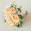 There is a soft, almost hushed charm to this hand-tied bouquet: creamy peach roses gathered close, their petals spiralling with a luminous, satin sheen, surrounded by an airy cloud of white gypsophila that gives the arrangement a dreamlike lightness. Each tiny baby's-breath blossom seems to pause the air around the roses, creating a soft-focus halo that frames the peaches and creams of the blooms. Polished green leaves emerge in measured intervals to anchor the piece, adding contrast and a quiet structural rhythm that prevents the design from feeling too ethereal. The stems are lovingly wrapped in peach satin ribbon and secured with a neat row of small pearls-an intimate, heirloom detail that catches the light like a small constellation when carried. In my experience working locally around Stanmore and Canons Park, brides often ask for this kind of gentle palette: romantic but restrained, fragrant yet fresh. The scent is light and clean, the tactile impression one of cool velvet petals and smooth ribbon beneath the fingers. Thoughtfully composed for ceremony or an intimate registry celebration, this bouquet reads both as a personal promise and a timeless decorative accent; a subtle, refined statement suited to quiet chapels, Georgian rooms, or alfresco photographs taken along Stanmore's leafy lanes.