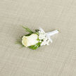 Laid carefully on a soft, woven surface that recalls elegant table linens in Stanmore's favourite wedding venues, this boutonnière radiates quiet sophistication and heartfelt intention. At its heart sits a creamy ivory rosebud, its silky petals held close, with just the slightest opening at the centre hinting at the fullness to come. Surrounding the rose, airy sprays of baby's breath form a gentle halo, their clusters of tiny white blooms softening the design with a romantic, cloud-like effect. Slender strands of fresh greenery, likely ornamental grass, weave and curl around the flowers, adding a touch of movement and a modern, garden-inspired feel-much like the lush planting around Stanmore Country Park or local church gardens. The stem is wrapped tightly in gleaming white satin ribbon, the wrapping so smooth and precise that it suggests the steady hands and practiced skill of a dedicated florist. A neat bow or final fold completes the look, reinforcing the sense that this is a piece created for a significant, joy-filled occasion. The neutral, textured background allows the creamy tones and crisp greens to stand out clearly, making each detail-from the velvety rose petals to the fine stems of gypsophila-easy to envision. One can almost feel the cool satin and the delicate brush of baby's breath as the boutonnière is pinned to a lapel. Ideal for a groom, best man, or special guest at a Stanmore wedding, this small arrangement becomes a meaningful symbol worn close to the heart.