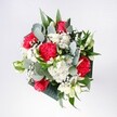 A hand-tied bouquet brimming with crimson roses, pink-red carnations, and soft white daisies is gathered tightly in a rounded, dome-like shape, as if just lifted from a florist's bench in Stanmore. The roses sit at the heart of the arrangement, velvety and full, their deep red petals spiralling inward and catching the light with a gentle sheen. Around them, ruffled carnations in rich tones of cherry and raspberry create a sense of movement, their feathery edges adding texture and a hint of playful drama. Small white chrysanthemums and daisy-like blooms are tucked between the bolder flowers, their snow-bright petals and sunny centres brightening the whole design like patches of morning sky. Threads of baby's breath weave delicately through the bouquet, tiny cloudlike blossoms that lend softness and an airy, celebratory feel. Eucalyptus stems arc gracefully outward, their muted green and silvery-blue leaves adding a cool contrast to the warm reds and pinks, while deeper tropical greenery forms a lush collar around the base. The overall impression is one of cheerful elegance, as if this bouquet were made to greet a loved one returning home along Stanmore Hill or to light up a birthday table near Canons Park. You can almost imagine the faint, mixed scent: the classic sweetness of roses, the gentle spice of carnations, and the clean, leafy freshness of eucalyptus. Every stem has been carefully placed, creating a composition that feels joyful yet composed, perfect for congratulations, a romantic surprise, or simply to bring a burst of colour and optimism into a quiet corner of a Stanmore home.