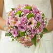 The spirit of Stanmore's garden-lined avenues comes alive in this radiant bridal bouquet, tenderly held against the pure white of a wedding gown. Soft lilac and blush pink roses bloom at its heart, their spiral petals releasing a subtle, fresh scent evocative of spring mornings in Hill House Gardens. Pops of lively lime green button chrysanthemums add a playful, modern flair, their round forms and crisp hues energising the arrangement. Delicate pink alstroemeria, with their distinctive streaked petals, infuse an exotic note, while clusters of cloud-like white baby's breath impart an airy innocence that lightens the mood. Deep green foliage peeks through, setting off the pastel palette with rich contrast. As the bouquet glows in the bride's hands, anticipation and serenity mingle-an emblem of happiness crafted by Flowers Stanmore and inspired by the natural elegance found throughout Stanmore's beloved parks and wedding venues. This bouquet tells a story of romance, artistry, and new beginnings, perfectly at home in a sun-filled celebration.