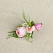 Arranged artfully on a pale, subtly textured linen backdrop typical of Stanmore's gracious events, this handcrafted boutonniere emanates warmth, freshness, and gentle romance. At the forefront is a beautifully formed pink rose, its petals coiled tightly in a classic spiral, set next to a soft Alstroemeria blossom in pale peach, each petal kissed with sunny yellow and delicate markings. Baby's breath enfolds the primary blooms with a light, cloudlike touch, while tiny, vibrant green cushion mums nestle throughout, adding pops of colour and texture that echo the vibrancy of Stanmore's beloved parks. The base of the arrangement is structured with a mix of slender, dark green grasses and broad, folded leaves, all expertly arranged to frame the flowers and add depth. The stems are elegantly bound by a gleaming fuchsia pink satin ribbon, tied into a neat bow whose rich sheen signals the celebratory spirit found at local weddings and milestones. The natural, woven fabric beneath provides a contrast that enhances the arrangement's delicate colours and detailed structure. Every element combines to evoke a sense of occasion and belonging-whether for a groom's lapel at a Stanmore wedding, a prom night at Bentley Priory, or a joyful gathering at a local venue, this boutonniere is an elegant, locally inspired touch crafted by Flowers Stanmore.