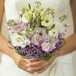 With the soft embrace of morning sunlight, this Stanmore bridal bouquet becomes a celebration of delicate textures and gentle hues, each bloom reflecting the joy of a wedding day set amidst HA7's leafy avenues. Creamy Lisianthus petals, ruffled and luminous, open in quiet homage to romance, their yellow-green centers bright with tender optimism. Scattered among them, pale green buds hint at stories yet unfolding, while airy clusters of lilac and blush-pink stock whisper sweetness-much like the subtle fragrance drifting through Stanmore's local gardens in June. Along the bouquet's base, vivid, star-shaped purple Allium blooms emerge, bringing playful contrast and a touch of artistic flair that nods to the vibrant beds of nearby Canons Park. Glossy bear grass loops above the Allium, securing the blossoms in an embrace both structured and fluid, reflecting the thoughtful design skills honed by Stanmore florists. The bride's graceful, softly polished hands cradle the bouquet, each detail-right down to the gentle shimmer of petals and the muted background of white lace-amplifying a sense of cherished intimacy. Here is a bouquet crafted not just for photographs but for memories, a keepsake of love and local pride that will linger in hearts long after the last petal falls.