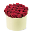 In a softly lit studio moment prepared for Flowers Stanmore, a lush, luxurious dome of deep red roses sits within a pale cream round gift box. The bouquet comprises roughly two dozen fresh, velvety crimson blooms, each blossom still tightly furled at the tip as if just opened to reveal its full romantic promise. The roses are packed so densely that the cylindrical form of the container is almost entirely filled, creating a sumptuous mass of color that rises slightly above the rim. Between the heads, wisps of dark-green foliage peek out, giving natural breath and a subtle frame to the sea of red. The box itself wears a smooth, matte ivory finish, a modern, premium presentation that recalls a classic hat box reimagined for luxury flower delivery. The composition is captured from a slightly elevated, three-quarter view, set against a clean white background that keeps the focus squarely on the flowers and their chic packaging. This image radiates the essence of a thoughtful, heartfelt gift: romance paired with refinement, celebration tempered with serenity. It speaks of Valentine's Day, anniversaries, or simply a moment of graceful affection, delivered with care to Stanmore homes and businesses. For residents of Stanmore and the surrounding northwest London districts, same-day delivery makes this stunning bouquet not just seen, but experienced, a testament to local craftsmanship and fresh, fragrant stems from our trusted growers. The scent of rose lingers in the air, inviting a pause to notice the texture and depth of each petal as light plays across the velvet surface. Craftsmanship and care lie at the heart of every stem in this striking arrangement.