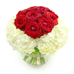 A classic, romantic arrangement is shown in bright, even lighting against a pure white backdrop, giving it a clean, contemporary feel. At the top of the design, a tidy dome of around ten deep red roses draws immediate attention. The roses are lush and velvety, their petals arranged in tight, layered spirals that speak of fullness and quality. Some blooms are just beginning to open, with outer petals gently softening, while others remain more compact, adding visual interest and depth. Cradling these roses is a substantial base of white hydrangeas, gathered into a full, rounded form that looks soft and cloud-like. Each hydrangea head is composed of many tiny, overlapping petals, creating a plush texture that contrasts with the smooth, sculpted look of the roses. The colour contrast between the intense crimson and the creamy white is dramatic yet elegant, evoking the feeling of a timeless love story-ideal for an anniversary or special celebration. The entire bouquet is presented in a clear, round glass vase, part-filled with water, where the green stems are visible, gently fanning out inside. The glass curves gently upward, catching small reflections of light that lend a polished finish to the scene. This bouquet could easily be imagined gracing a table in a home near Stanmore Golf Club, or set in a bay window along Marsh Lane, bringing a sense of romance and sophistication into the room. It feels like a floral tribute to enduring affection, carefully constructed by a florist who understands how to balance passion with subtlety.