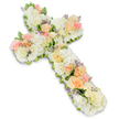 A reverent floral cross, carefully crafted as a sympathy tribute, is shown in full against a luminous white background that gives the image a calm, chapel-like atmosphere. The cross itself is created entirely from flowers, with no visible supports, resulting in a soft-edged, inviting shape. The main impression is one of creamy whites and ivories, with thick, cushiony clusters of hydrangea-style blooms forming the lush base and numerous white roses woven throughout to add definition and elegance. Interlaced with these pale flowers, pastel roses in muted peach, apricot, and gentle pink tones introduce a warm, comforting glow, like a soft sunrise across the cross. Small accents of pale lavender or light purple filler flowers appear sparingly, offering fine detail and a delicate contrast that enriches the overall design. Along the edges, subtle glimpses of green foliage can be seen, framing the floral surface and providing visual depth without disrupting the serenity of the colour palette. The professional lighting ensures each petal and curve is clearly visible, giving the arrangement a sense of freshness and care. This is the kind of floral cross families in Stanmore might choose for a funeral, wake, or memorial service, perhaps after gathering together near the shops and green spaces of the area before making their way to a local chapel. It conveys sympathy, faith, and quiet hope, serving as a central floral expression of love and respect for someone deeply missed.