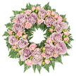 A refined, circular funeral wreath is shown laid flat against a pure white background, its symmetry and fullness immediately catching the eye. The entire ring is composed of elegantly arranged roses and rich foliage, giving the impression of a carefully considered design, like those often prepared for services in Stanmore. The main blooms are large, fully open roses in muted tones of dusty lavender, antique mauve, and soft grey-purple, evenly spaced around the circle. Their petals are lush and many-layered, curling in gentle waves that form soft, shadowed centres and add a feeling of depth and tenderness. Interspersed throughout are clusters of smaller blush pink spray roses, ranging from tight buds to half-opened blossoms, which introduce a delicate contrast in both size and colour. These pastel accents lighten the palette and suggest a sense of gentleness and grace. All of the flowers rest on a dense foundation of dark green fern fronds, likely leatherleaf or sword fern, whose finely cut, serrated leaves fan outward beyond the blossoms and peek through the spaces between them. The deep greenery adds structure and frames the softer tones with a natural, almost woodland edge. Tiny glimpses of darker filler greens and small budding elements are tucked among the roses, giving the wreath a subtle depth that rewards a longer look. The lighting is soft and even, allowing the colours to appear true and the textures to feel almost touchable. Together, the lavender and pink hues, set against the deep green, create a wreath perfectly suited for a memorial, funeral, or celebration of life in Stanmore, offering a quiet message of love, respect, and peaceful farewell.