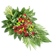 Presented on a plain white background, this long, elegant sympathy spray flows from a fuller base to a delicate tip, creating a graceful line that suggests both movement and calm. The central body of the arrangement is formed by rich dark red flowers: classic velvety roses in varying stages of bloom, bold red gerbera daisies with distinct dark centres, and clusters of ruffled carnations that add soft volume. These reds create an intense, heartfelt core, speaking of devotion and remembrance. Threaded through this are clusters of vivid lime green chrysanthemum button pompons, each small, rounded head adding a bright, contemporary counterpoint that lifts the entire piece. Scattered among the stronger colours are little white filler flowers, perhaps tiny daisies or gypsophila, their delicate petals introducing lightness and a hint of quiet purity, like the pale skies often seen over Stanmore's open green spaces. A generous frame of foliage supports and shapes the spray: broad, glossy dark green leaves form a secure base and backdrop, feathery fern fronds soften the outline, and other mixed greenery adds depth and layered texture. At the lower right, several long, broad green leaves are fanned out purposefully, accenting the elongated teardrop silhouette, while at the upper left, a vertical grouping of straight green stems stands upright, bound visually by a wide leaf wrapped artfully around their base. Suitable as a casket spray or a standing tribute for services in Stanmore churches and crematoria, this arrangement offers a quietly powerful expression of sympathy, blending timeless red blooms with fresh green and white accents to honour a loved one with dignity and grace.
